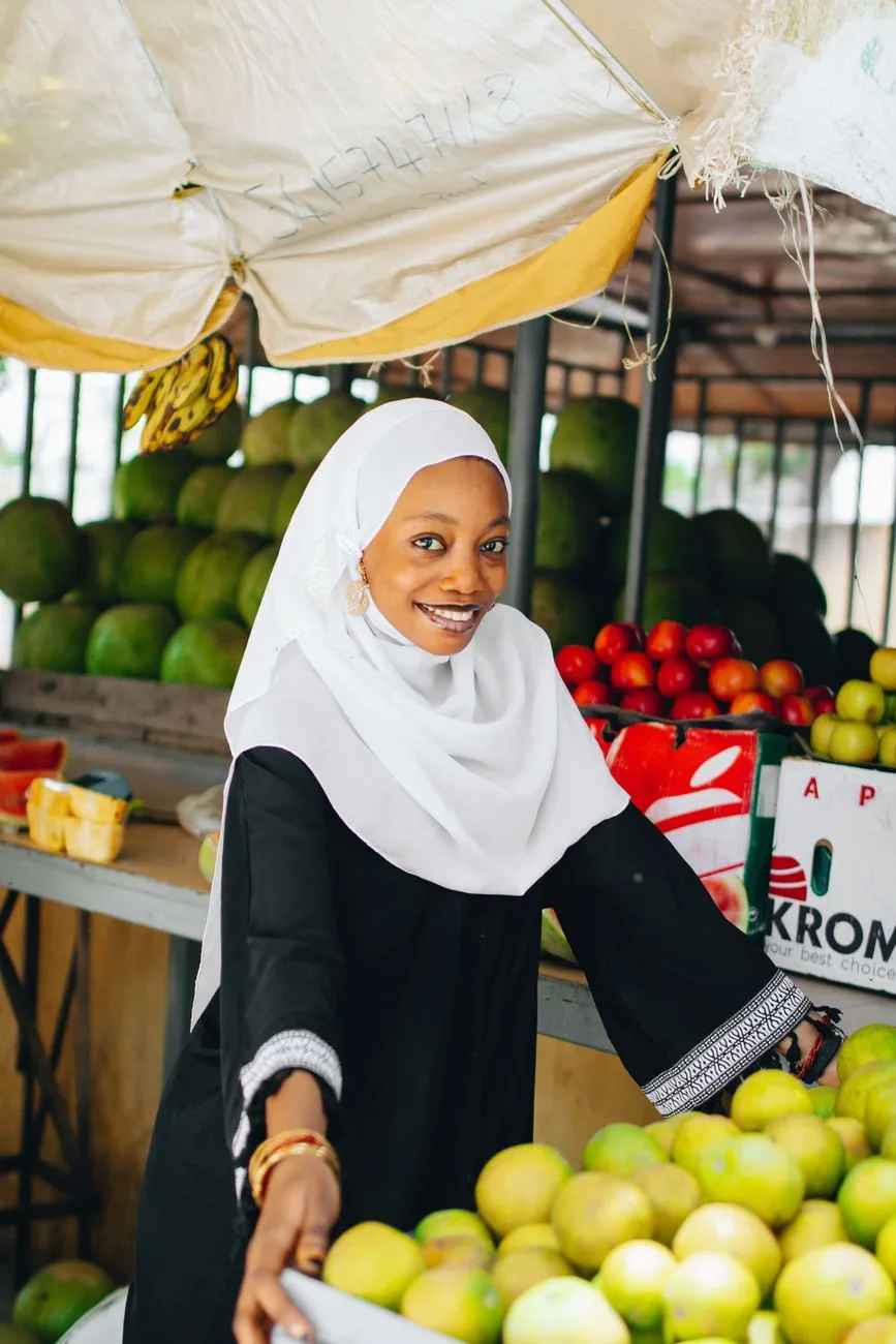 A market trader smiling behind her fruit stall