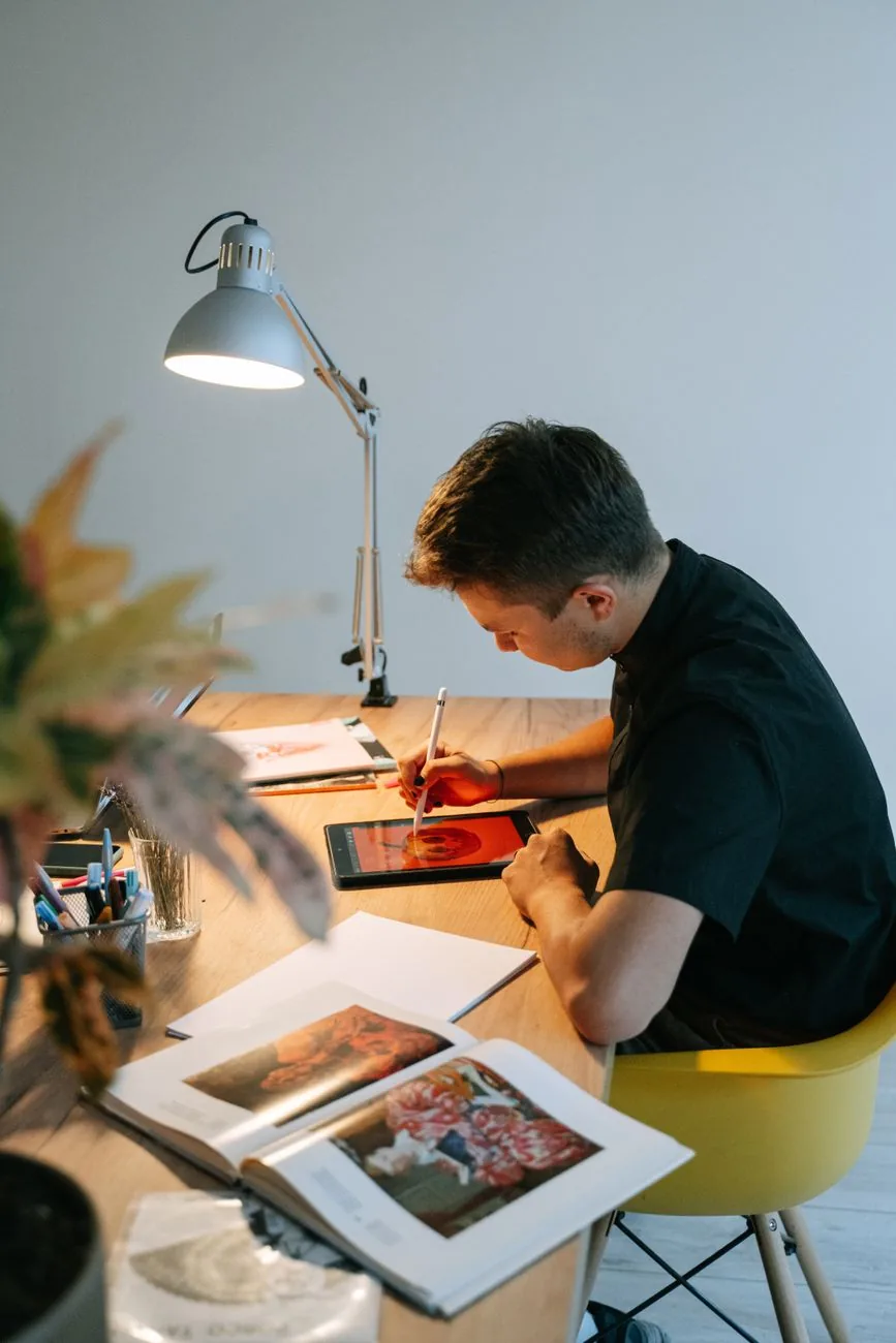 A designer drawing on a tablet at a lamplit desk