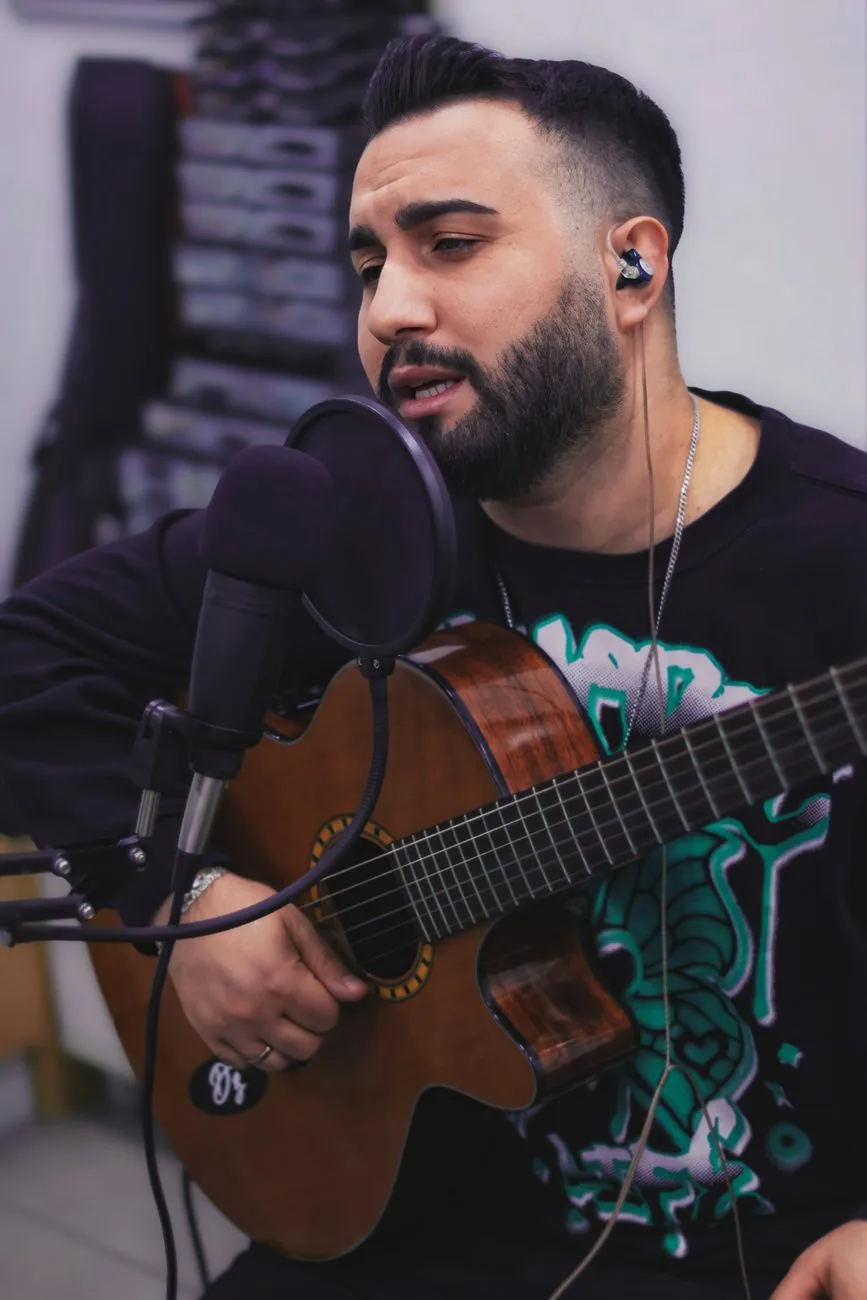 A musician singing into a microphone with an acoustic guitar